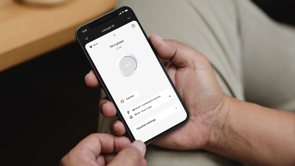 Hand holding iPhone running Easee app showing 46% charge ring, 24 of 34kW grid capacity and Equalizer settings on TN 3-phase install